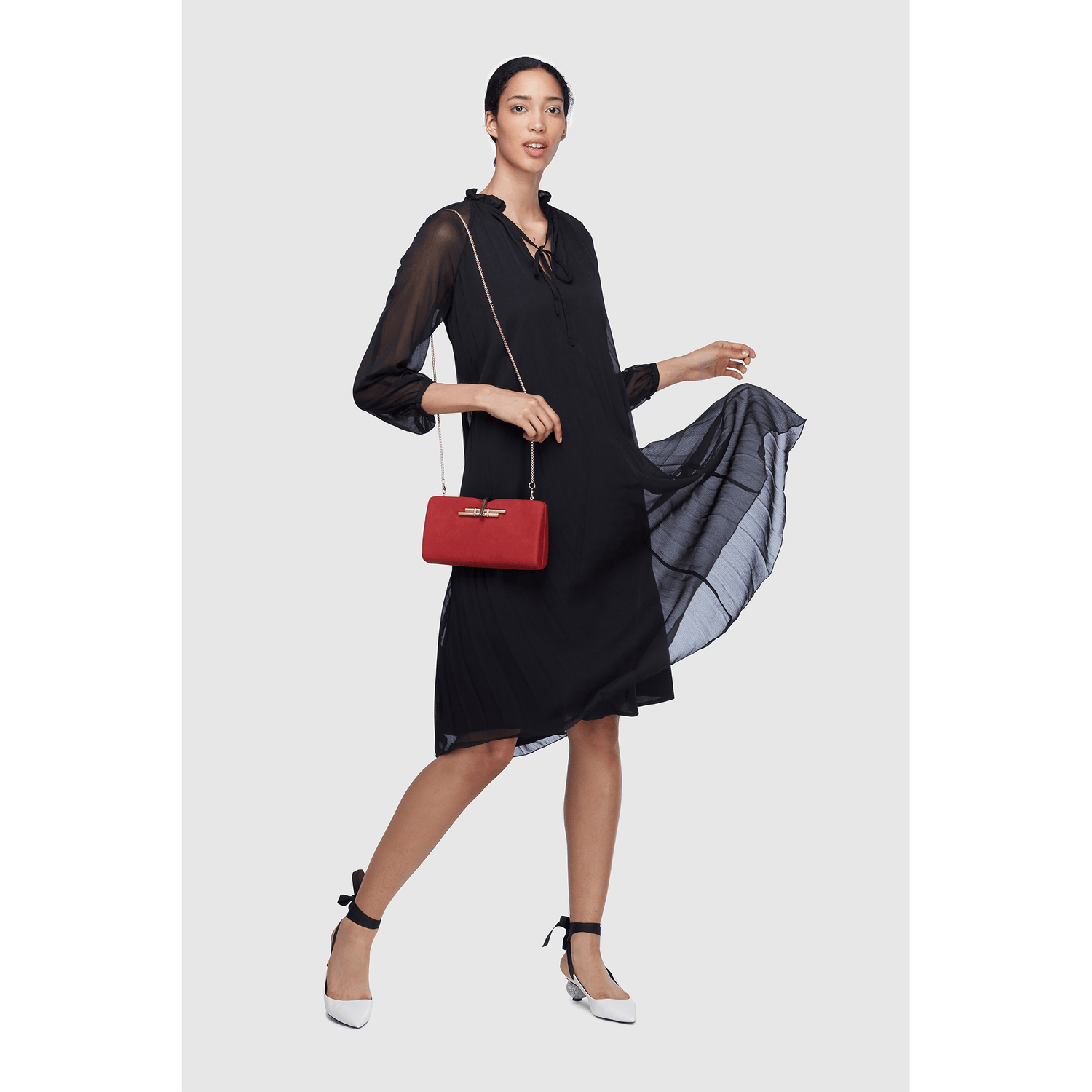 Elegant model wearing a black dress, showcasing a stylish red handbag from the sustainable wallets and bags collection