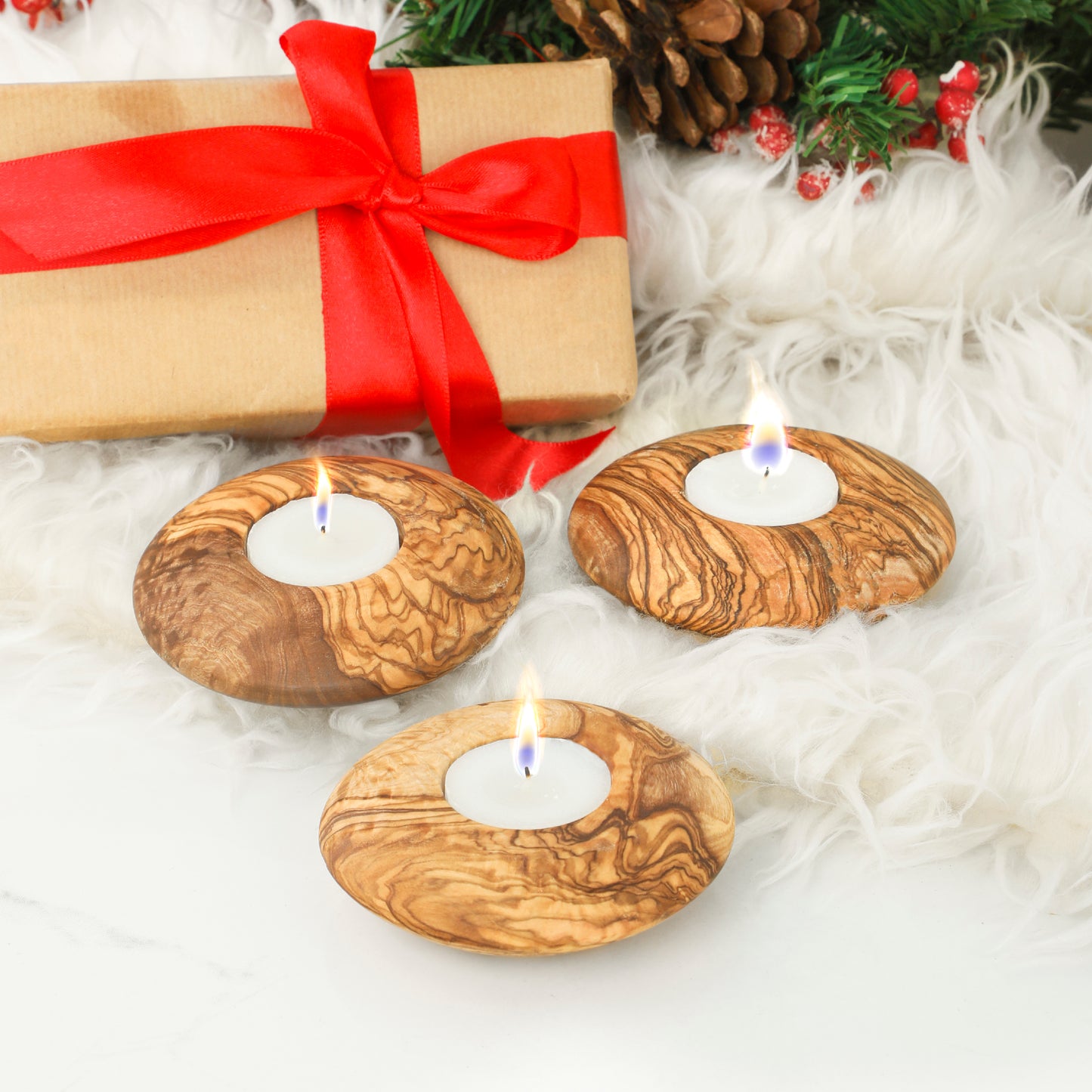Set of three olive wood candle holders with white candles, beautifully displayed with festive decorations