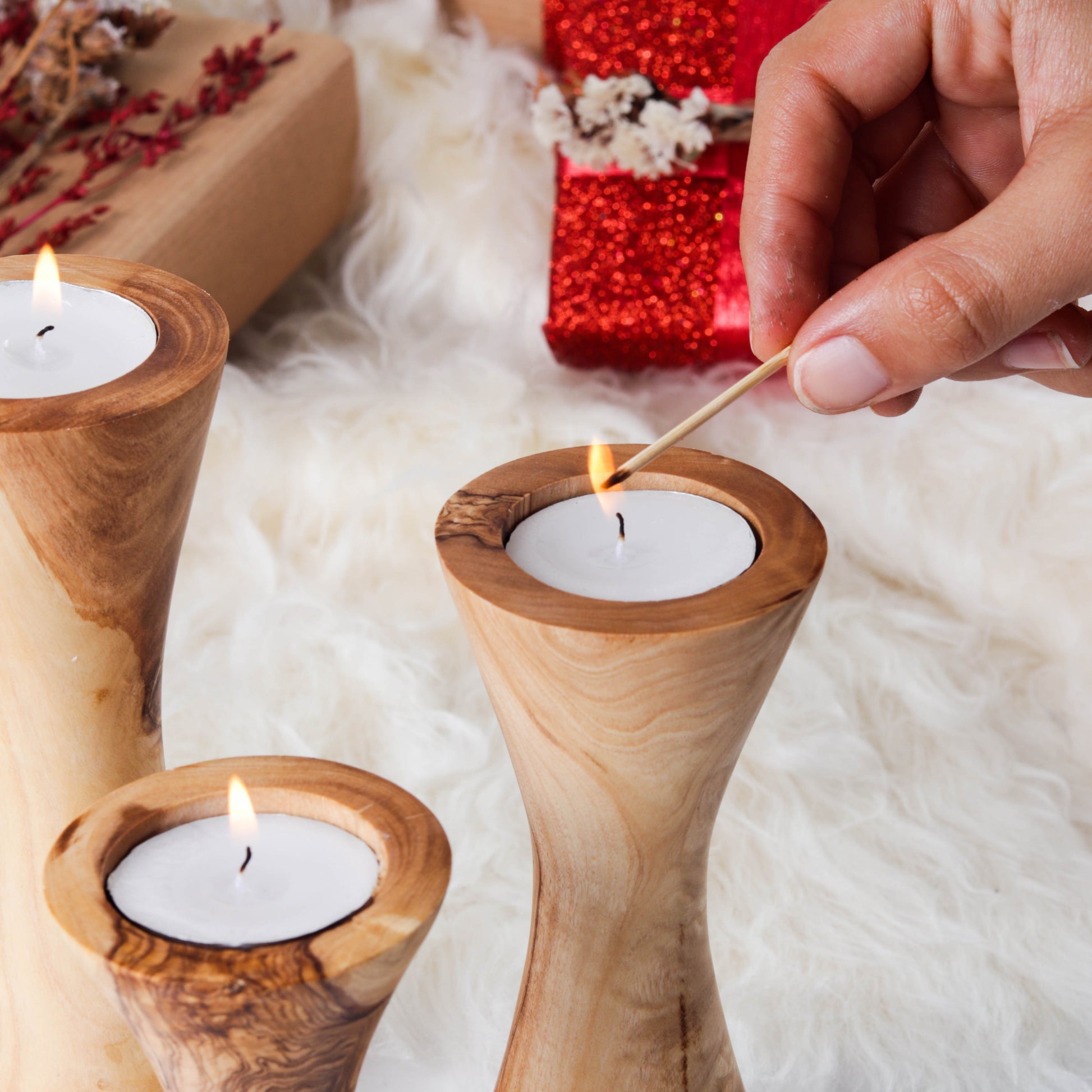 Three handcrafted olive wood candle holders with burning tealights, perfect for home decor