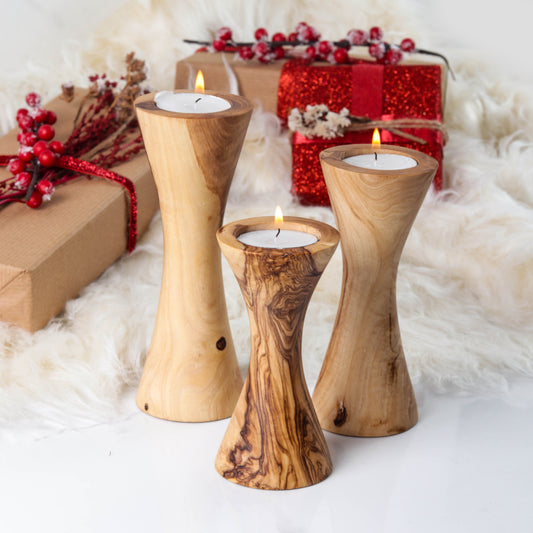 Set of three handcrafted olive wood candle holders with elegant designs and warm candles, perfect for decor